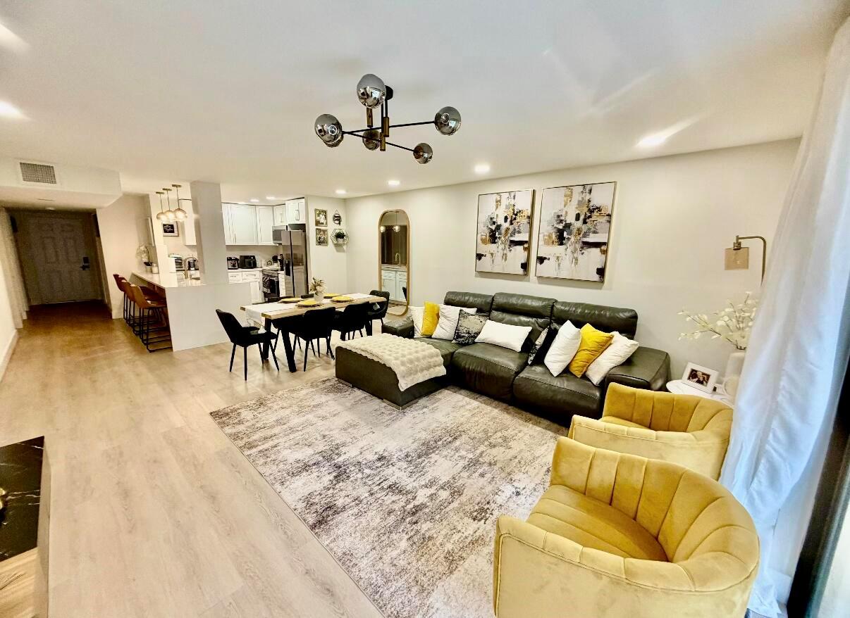 An open-concept living and dining area features a sectional sofa, yellow armchairs, and kitchen — 22415 SW 61st Way # 106, Boca Raton FL 33428, BOCA RATON, FL