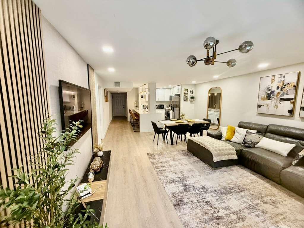 An open-concept living and dining area features wood-slat wall paneling, light flooring, and modern lighting — 22415 SW 61st Way # 106, Boca Raton FL 33428, BOCA RATON, FL