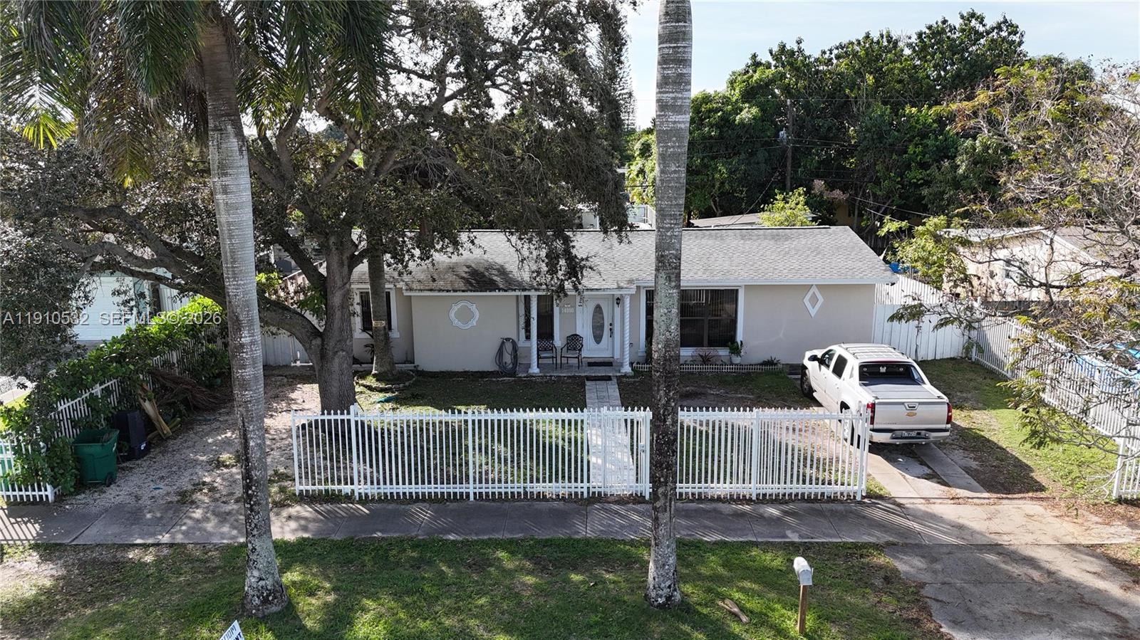 A single-story house with a white fence, a driveway, and two tall palm trees — 14800 SW 296th St, Homestead FL 33033, HOMESTEAD, FL