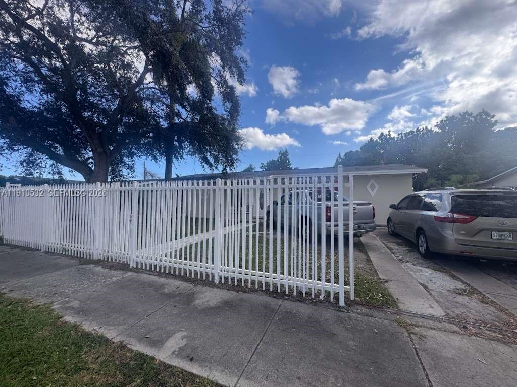 A white vinyl fence encloses the front yard of a single-story house with two vehicles — 14800 SW 296th St, Homestead FL 33033, HOMESTEAD, FL
