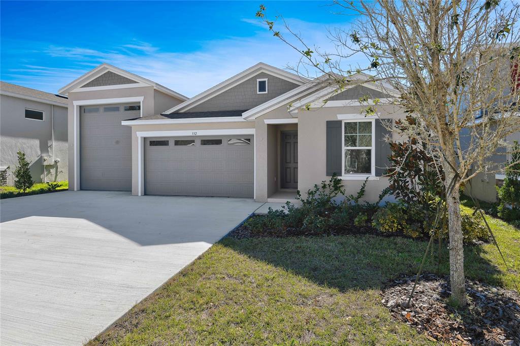 A single-story house with a two-car garage, gray siding, and a concrete driveway — 332 ALEXANDRITE STREET, DELAND, FL