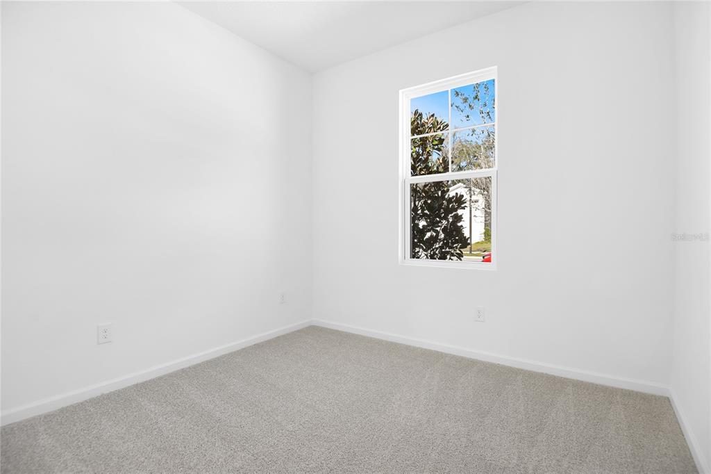 An empty bedroom features white walls, gray carpet, and a single window — 332 ALEXANDRITE STREET, DELAND, FL