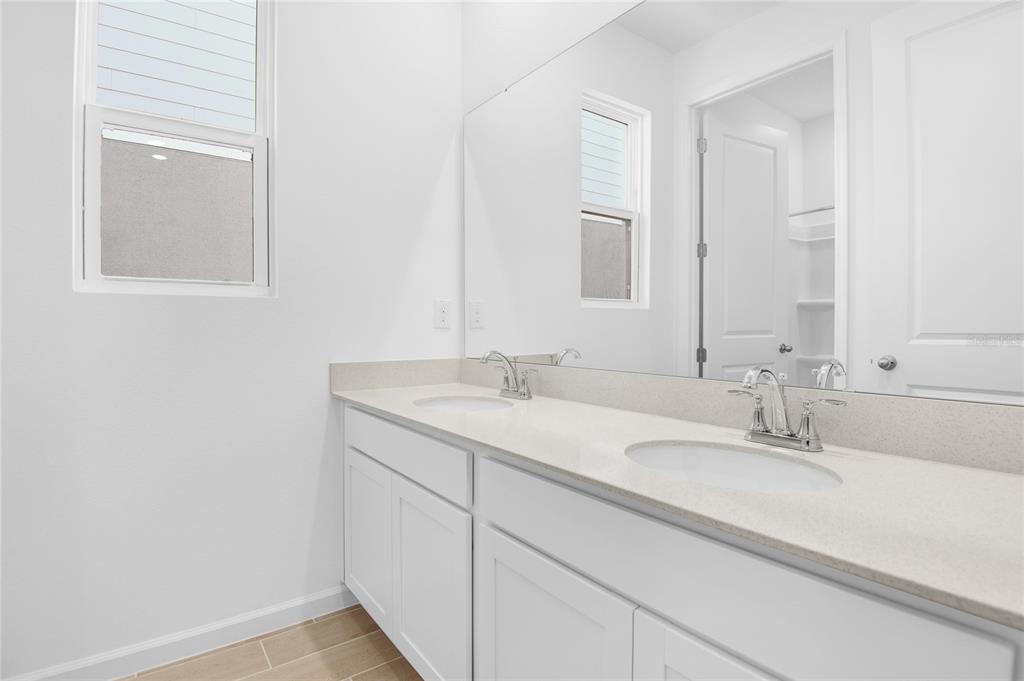 A bathroom features a double vanity with white cabinets, a light countertop, and a large mirror — 332 ALEXANDRITE STREET, DELAND, FL
