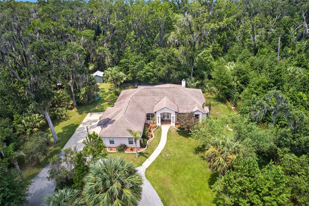 An aerial view of a single-story house surrounded by dense trees and a grassy yard — 19040 NW 88TH AVENUE ROAD, REDDICK, FL
