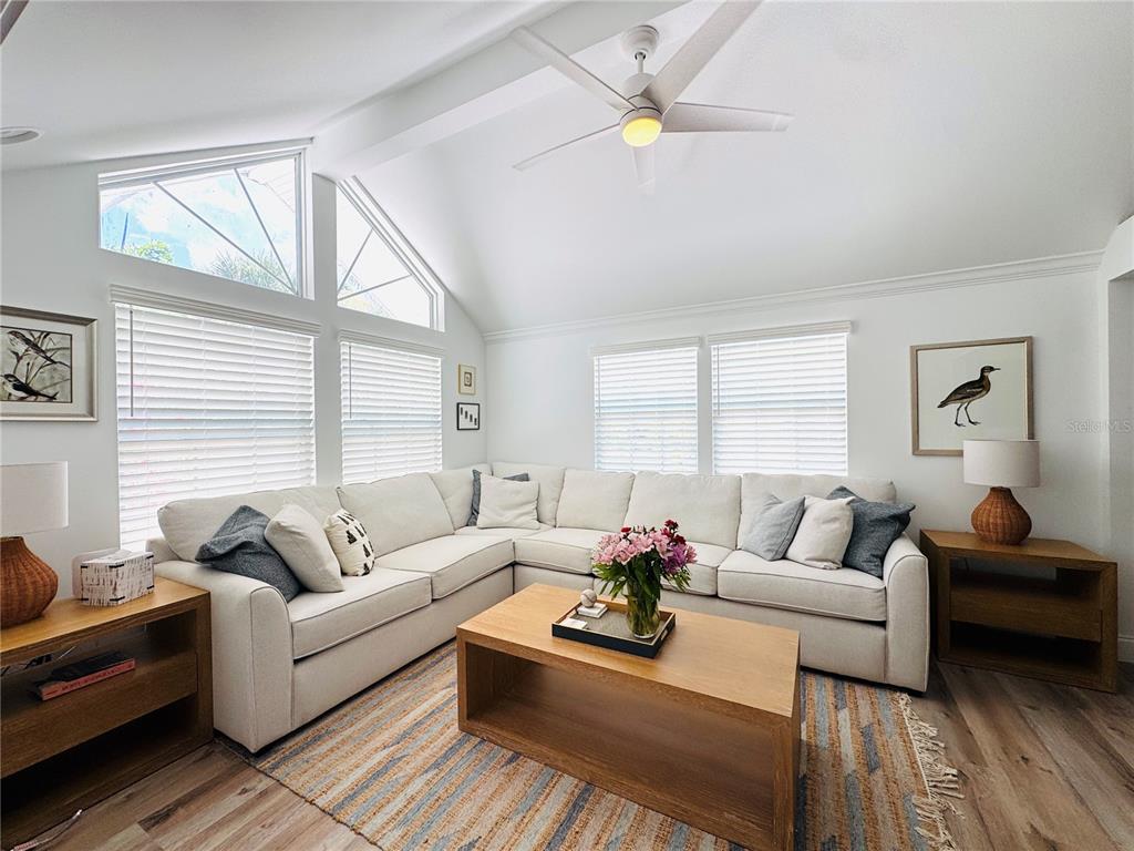 A bright living room features a white sectional sofa, a wooden coffee table, and vaulted ceilings — 701 BROADWAY STREET, LONGBOAT KEY, FL