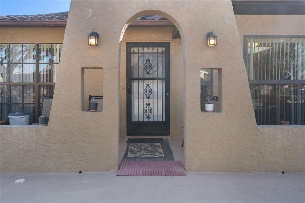 The exterior entrance features a stucco archway, a black security door, and two wall niches — 8914 SCHRADER BOULEVARD, PORT RICHEY, FL