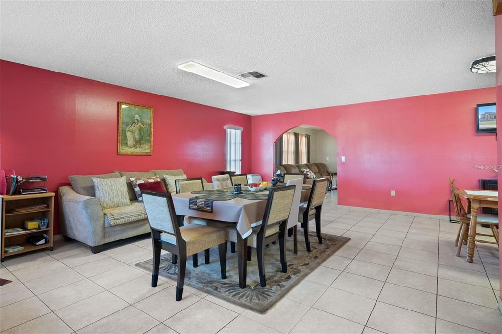 A dining area with a table and chairs sits in front of a bright red wall — 8914 SCHRADER BOULEVARD, PORT RICHEY, FL