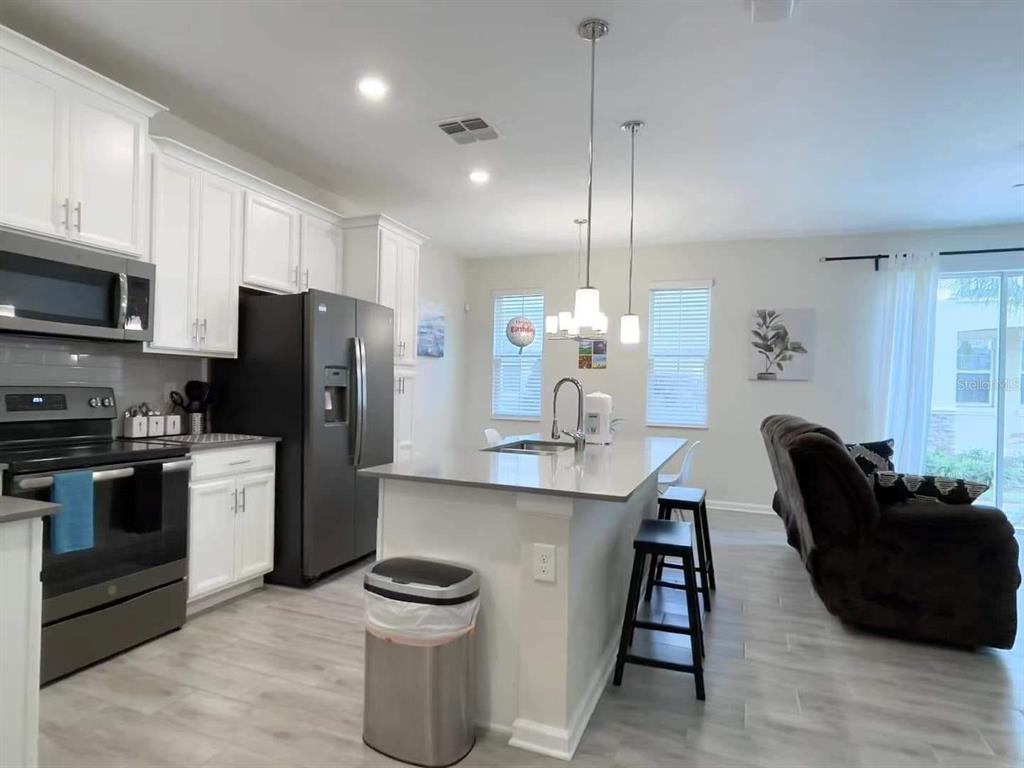 A kitchen with white cabinets, stainless steel appliances, a center island, and light wood flooring — 1312 SHINNECOCK HILLS DRIVE UNIT 1312, DAVENPORT, FL