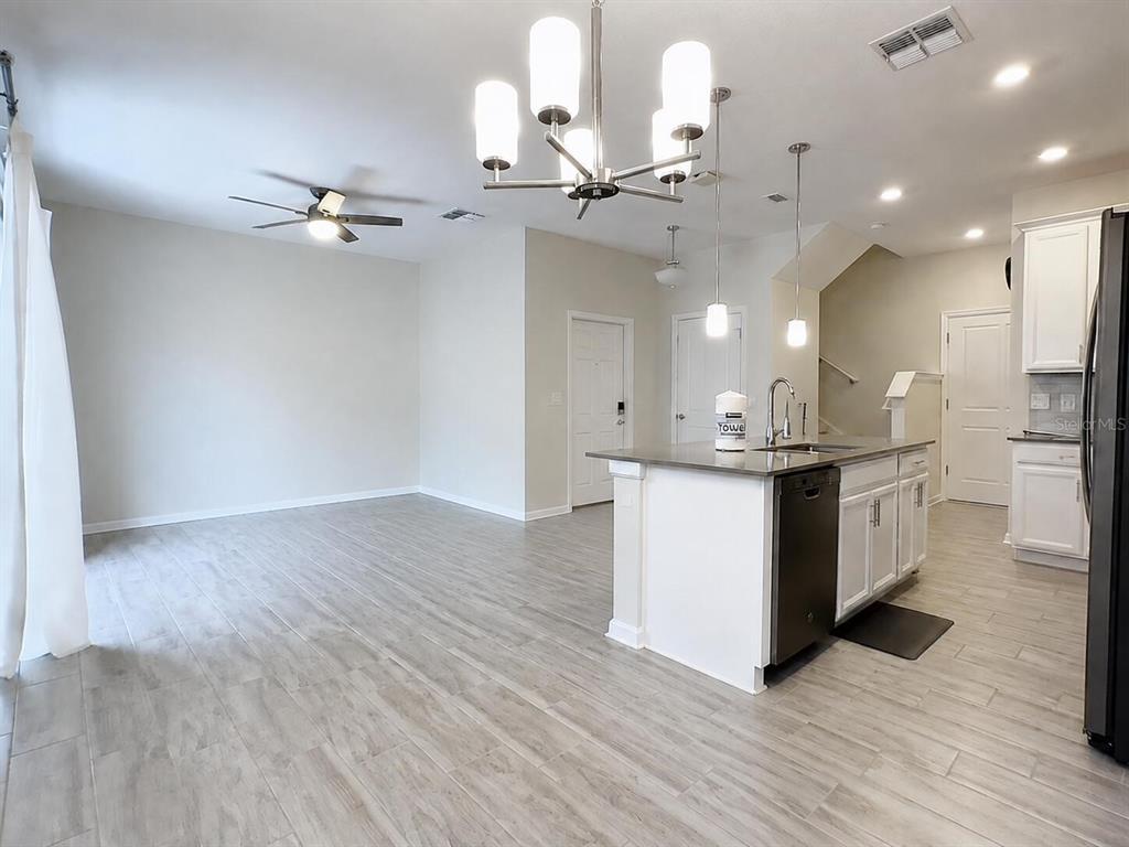 A kitchen island with a sink sits in an open-concept room with light wood-look flooring — 1312 SHINNECOCK HILLS DRIVE UNIT 1312, DAVENPORT, FL