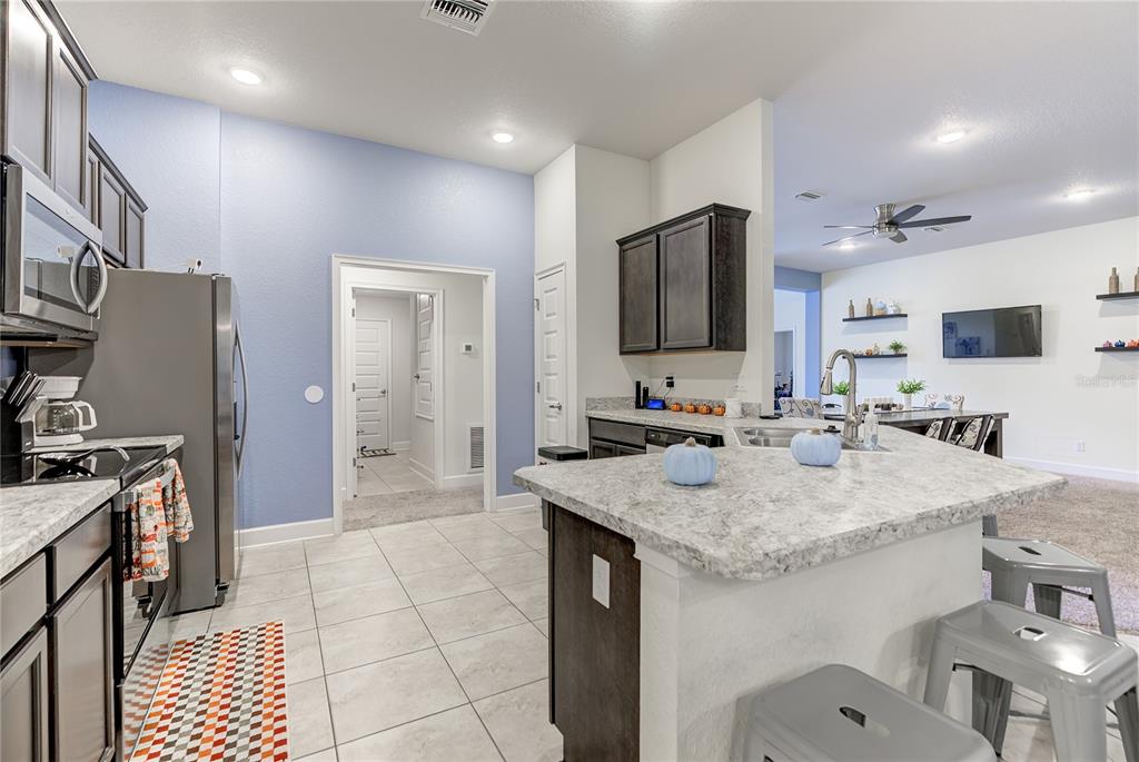 A kitchen features dark wood cabinets, stainless steel appliances, and a light-colored stone island — 71 BELLS OF IRELAND COURT, HOMOSASSA, FL
