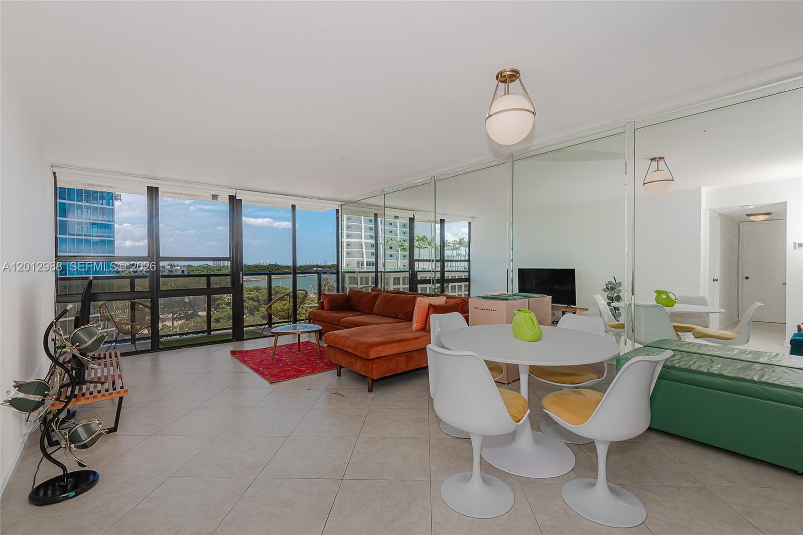 A living and dining area features floor-to-ceiling windows, mirrored walls, and tile flooring — 600 NE 36th St # 706, Miami FL 33137, MIAMI, FL