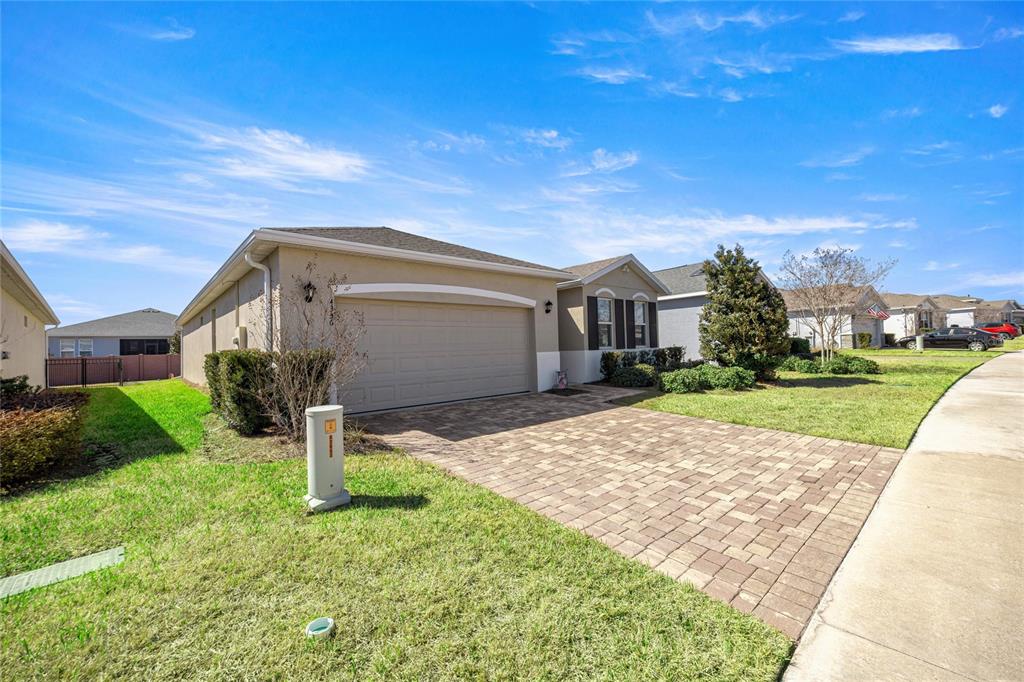 A single-story suburban house features a beige exterior, a two-car garage, and a paver driveway — 4336 NW 55TH COURT, OCALA, FL