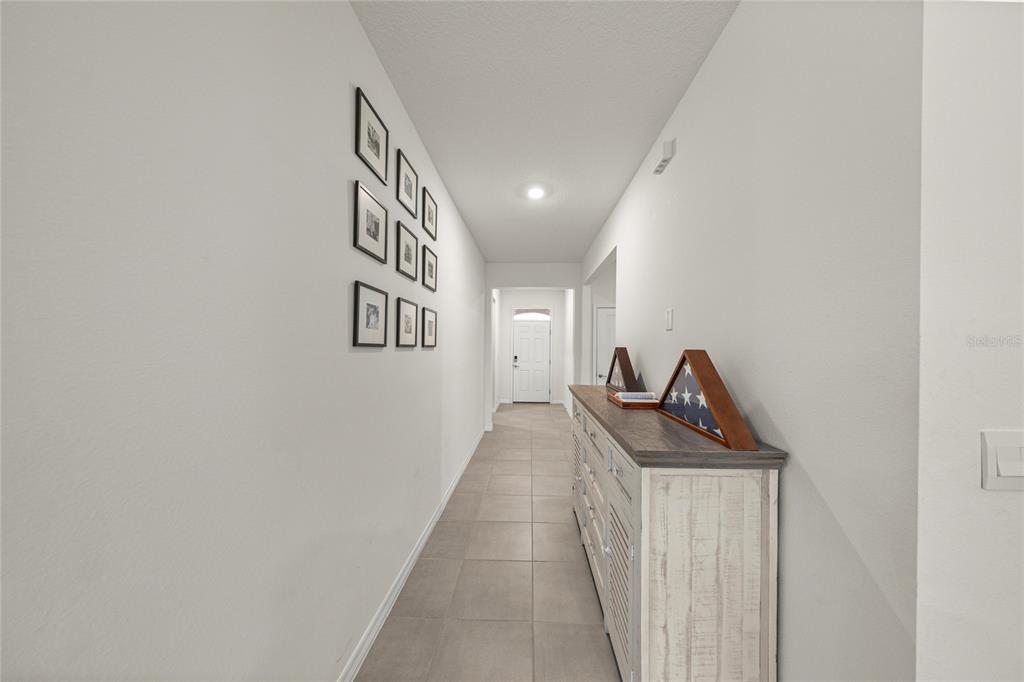 A hallway features light tile flooring, a white console table, and a gallery wall — 4336 NW 55TH COURT, OCALA, FL