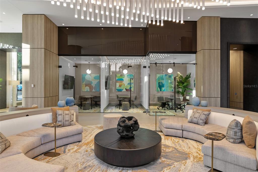 A modern lobby features curved sofas, a central coffee table, and glass-enclosed meeting rooms — 275 1ST AVENUE S UNIT 3205, ST PETERSBURG, FL