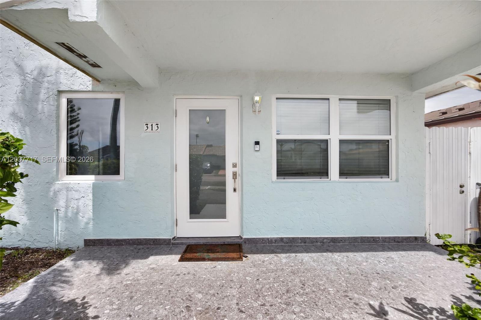 The exterior of a light blue house features a front door, windows, and a porch — 313 NW 132nd Pl, Miami FL 33182, MIAMI, FL