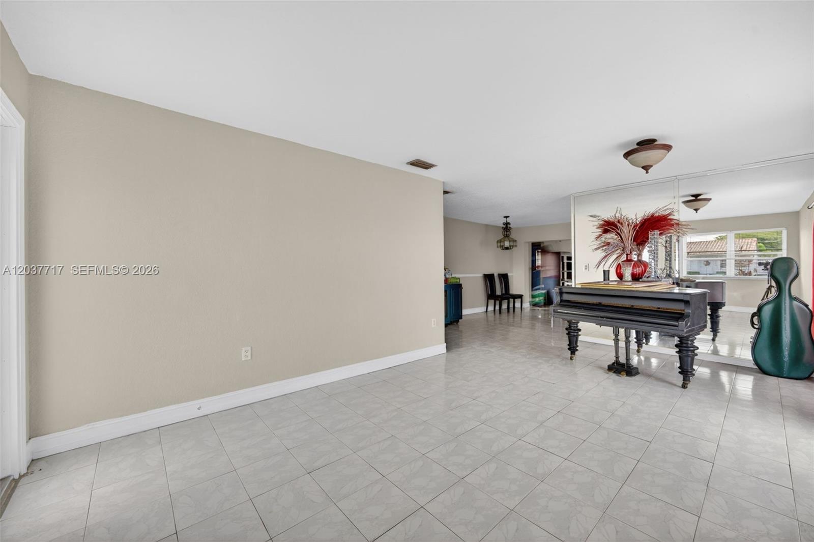 A tiled room features a grand piano, a mirrored wall, and an adjacent dining area — 313 NW 132nd Pl, Miami FL 33182, MIAMI, FL