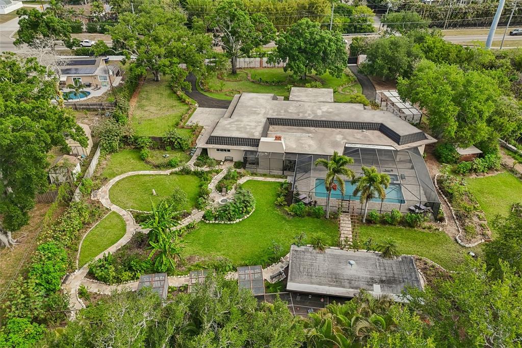 An aerial view shows a house with a screened pool, landscaped yard, and walking paths — 1875 BELLEAIR ROAD, CLEARWATER, FL