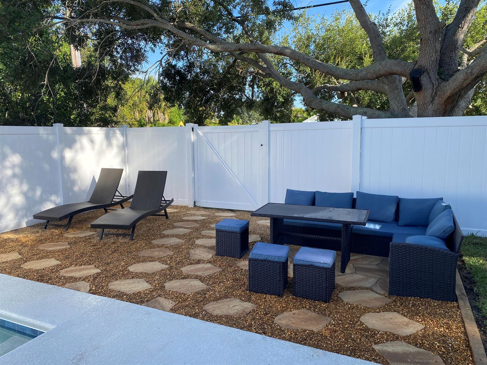 A backyard patio features a stone and gravel floor, lounge chairs, and outdoor dining furniture — 1510 3rd Court, Vero Beach FL 32960, VERO BEACH, FL