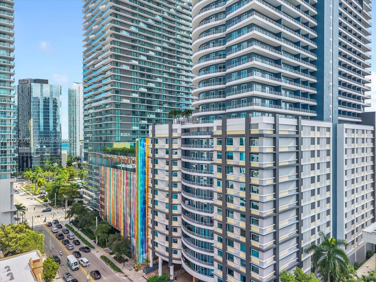 An exterior view of several modern high-rise apartment buildings featuring a colorful vertical mural — 40 SW 13th St # 202, Miami FL 33130, MIAMI, FL