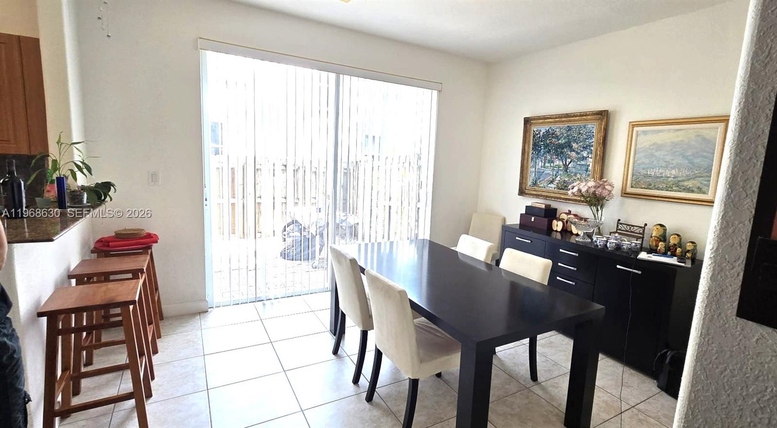 A dining room features a dark table, white chairs, a black sideboard, and sliding doors — 10840 NW 79th St, Doral FL 33178, DORAL, FL
