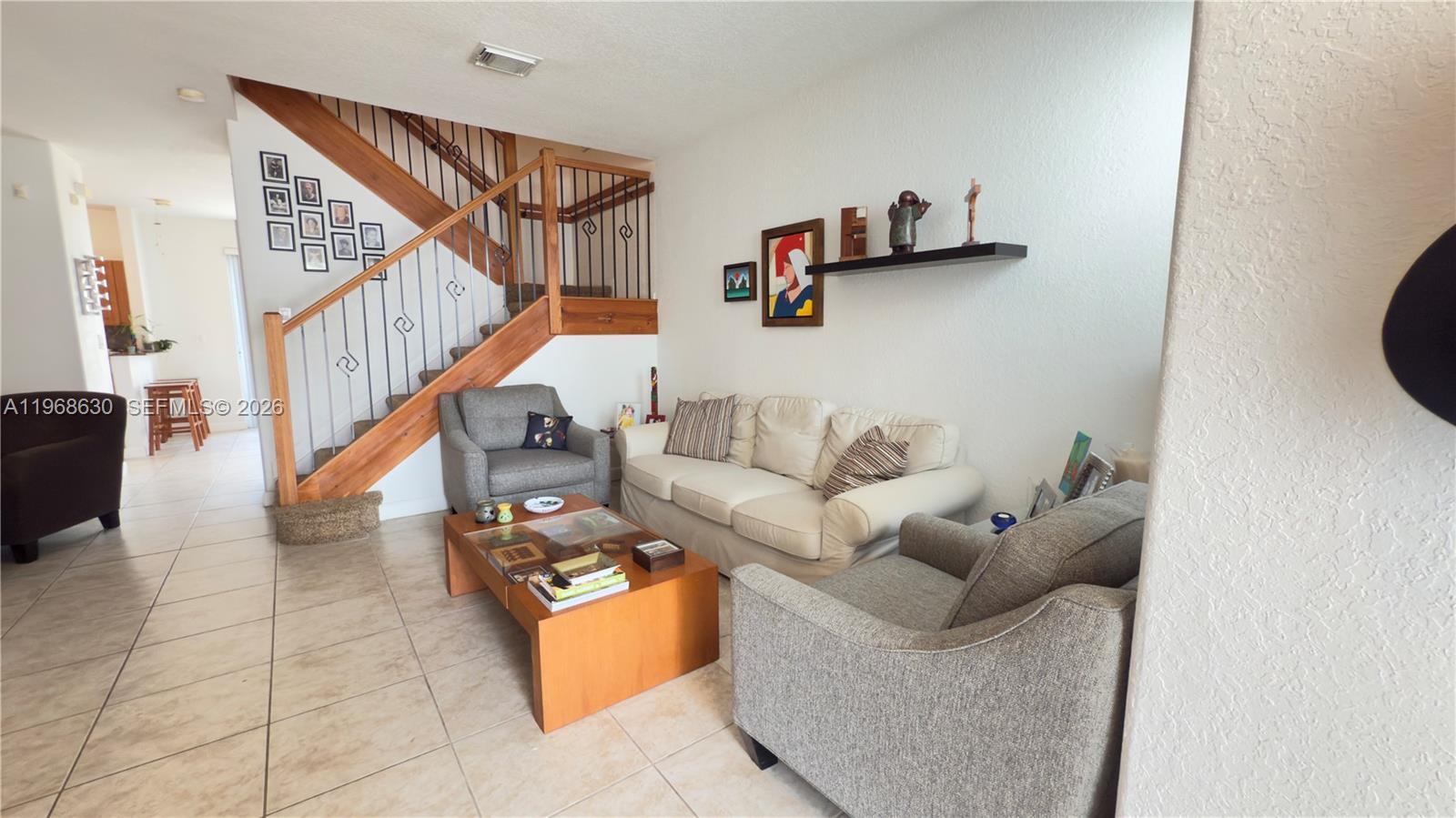 A living room features a wooden staircase, tile flooring, a sofa, and two armchairs — 10840 NW 79th St, Doral FL 33178, DORAL, FL