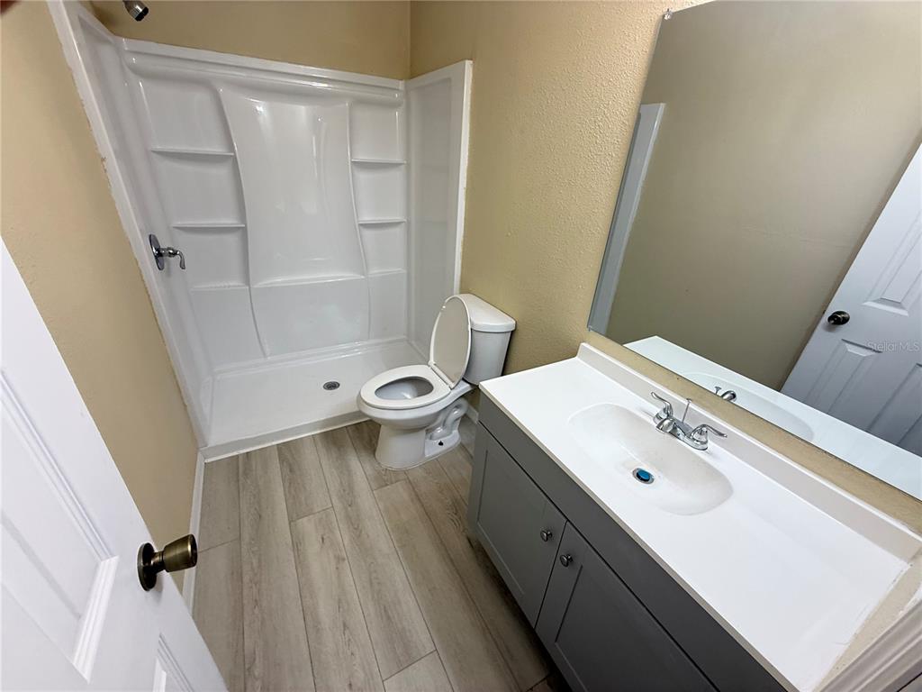 A bathroom features a gray vanity, a white toilet, and a white shower stall — 13917 3RD STREET, DADE CITY, FL