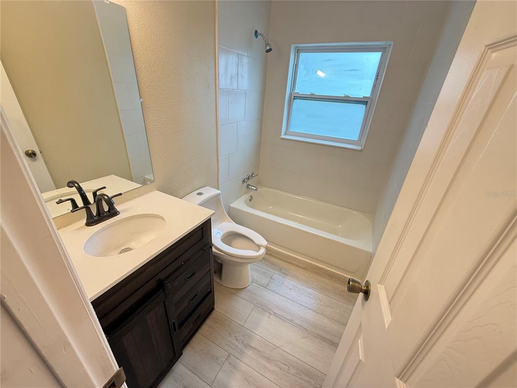 A bathroom features a dark wood vanity, a white toilet, and a tub-shower combination — 13917 3RD STREET, DADE CITY, FL