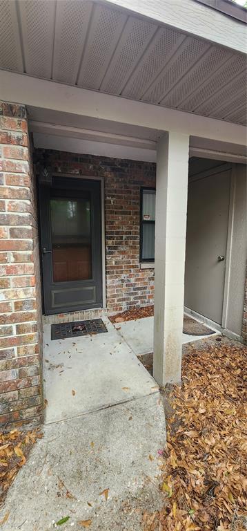 A brick exterior features a front door and a separate utility closet under a porch — 3404 NW 52ND TERRACE, GAINESVILLE, FL