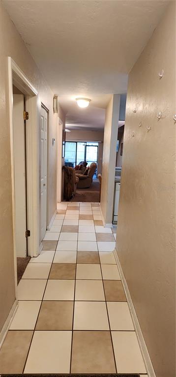 A hallway with light-colored tile flooring leads toward a living area with carpeted floors — 3404 NW 52ND TERRACE, GAINESVILLE, FL