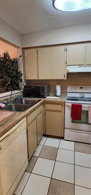 A kitchen features beige cabinets, a white stove, a dishwasher, and a tiled floor — 3404 NW 52ND TERRACE, GAINESVILLE, FL
