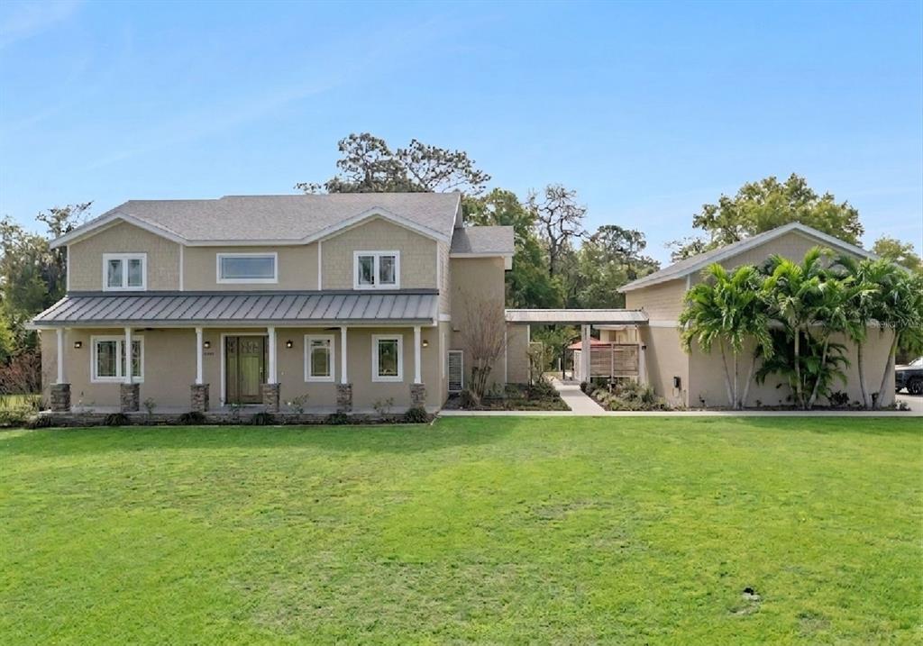 A two-story house with a metal-roofed porch and a detached garage connected by a walkway — 15503 TROTTING HORSE LANE, TAVARES, FL