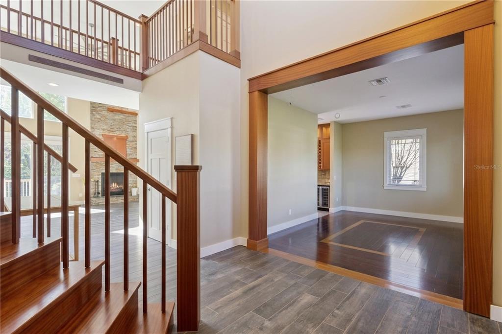 A foyer with a wooden staircase, tile flooring, and an open doorway to a room — 15503 TROTTING HORSE LANE, TAVARES, FL