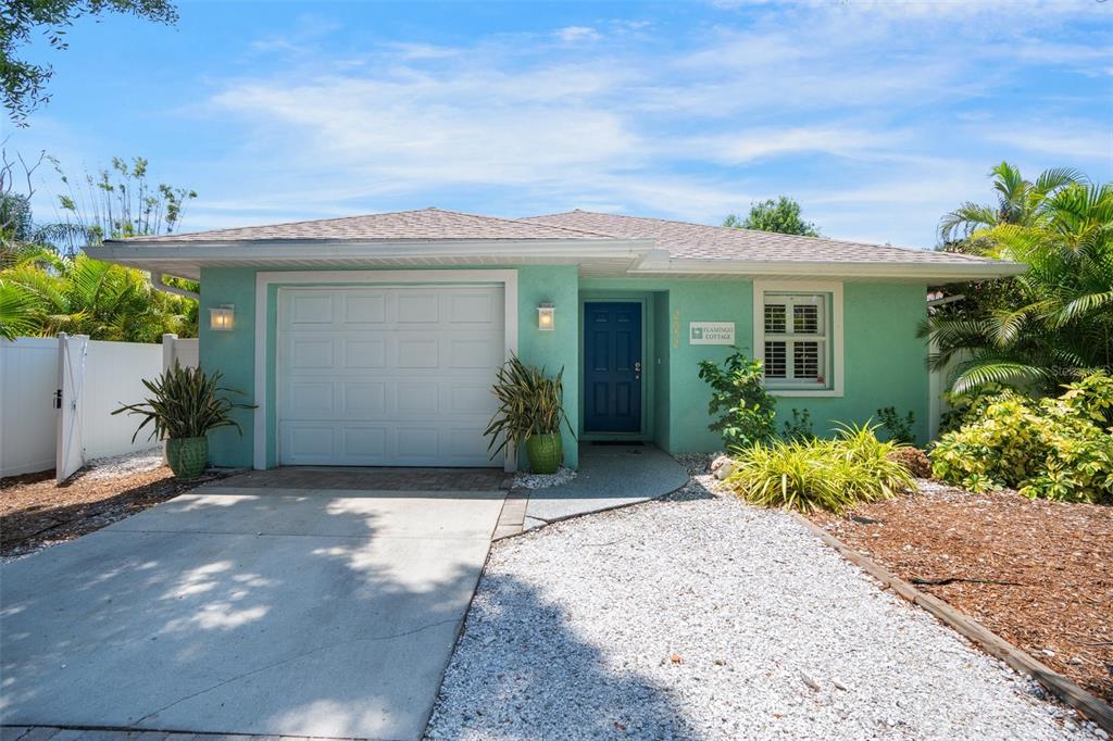 A single-story mint green house features a white garage door, blue front door, and gravel driveway — 2051 ROSELAWN STREET, SARASOTA, FL