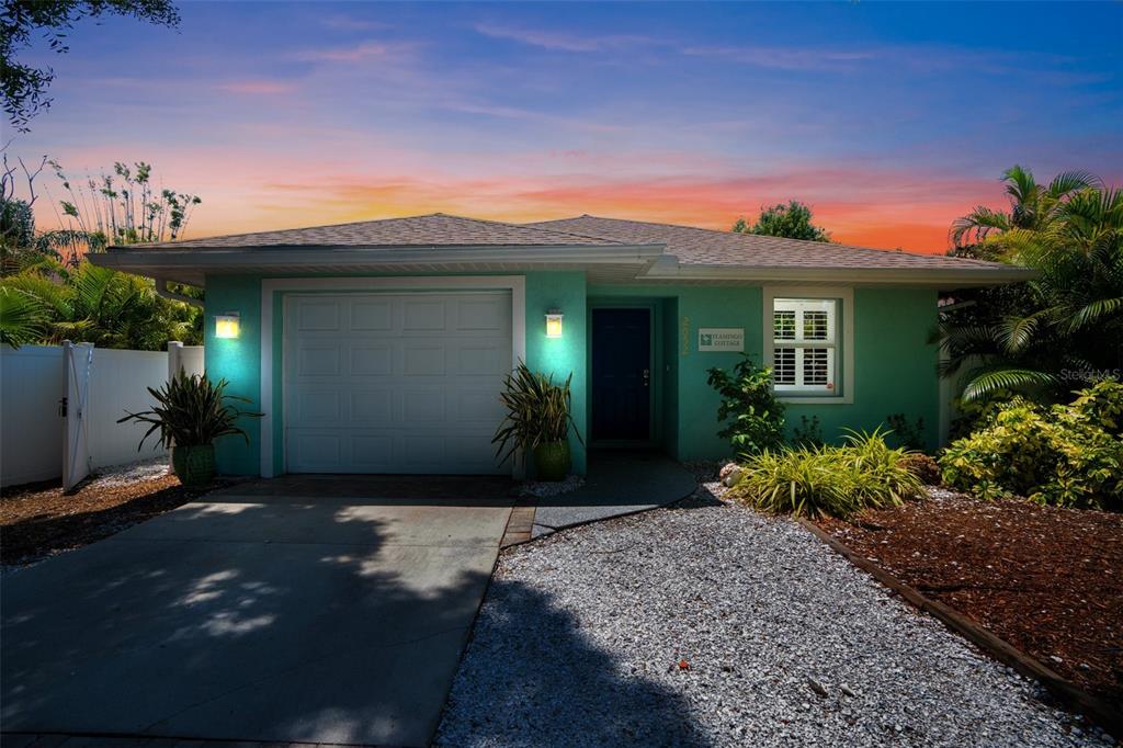 A teal single-story house features a white garage door, a dark blue front door, and gravel landscaping — 2051 ROSELAWN STREET, SARASOTA, FL