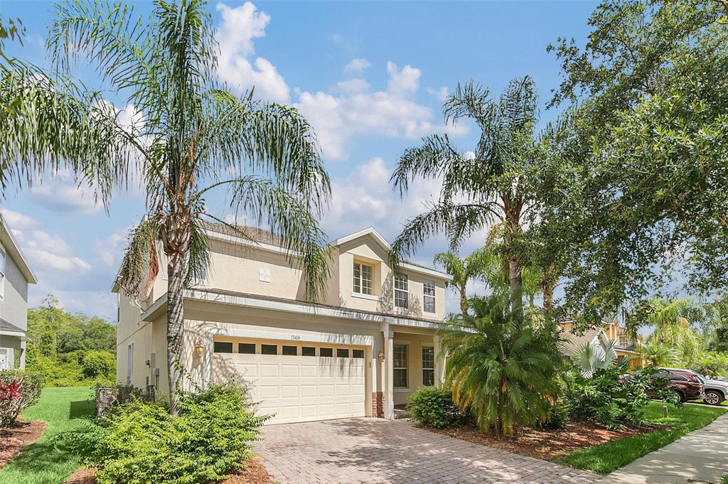 A two-story house with a beige exterior, a two-car garage, and palm trees in front — 13406 BUDWORTH CIRCLE, ORLANDO, FL