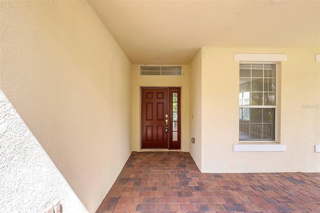 A covered entryway features a brown front door with a sidelight and brick pavers — 13406 BUDWORTH CIRCLE, ORLANDO, FL
