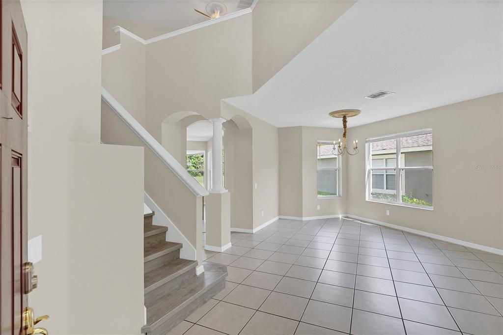 An entryway with a staircase, tiled floors, and a dining area with a chandelier — 13406 BUDWORTH CIRCLE, ORLANDO, FL