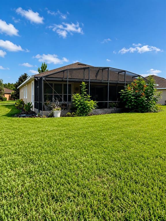 The exterior of a house features a large screened-in patio and a spacious green lawn — 766 CARMEL LANE, KISSIMMEE, FL