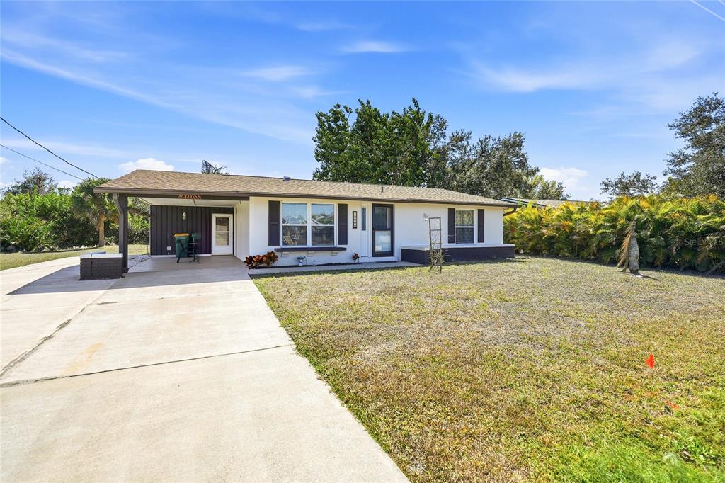 A single-story house with a white exterior, dark shutters, and a concrete driveway — 19909 MIDWAY BOULEVARD, PORT CHARLOTTE, FL
