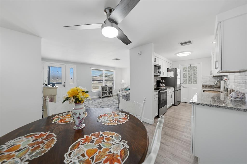 A dining area with a round wooden table opens into a kitchen and living room — 19909 MIDWAY BOULEVARD, PORT CHARLOTTE, FL