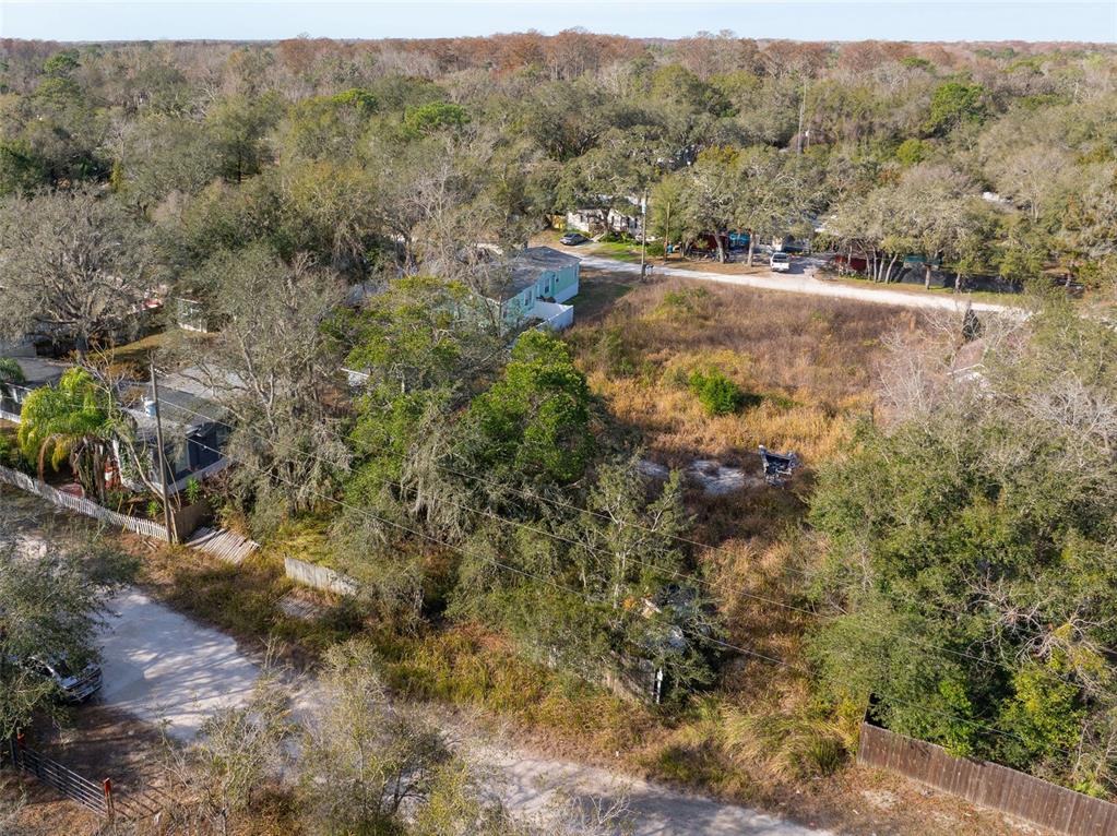 An aerial view shows a vacant, overgrown lot surrounded by trees and nearby residential houses — 00 BURTON STREET, NEW PORT RICHEY, FL