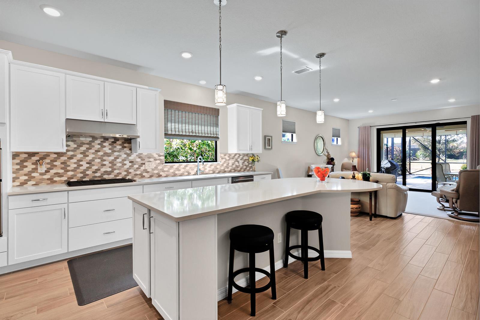 A bright kitchen features white cabinets, a large island with bar stools, and tile flooring — 5021 Monroe Circle, Vero Beach FL 32967, VERO BEACH, FL