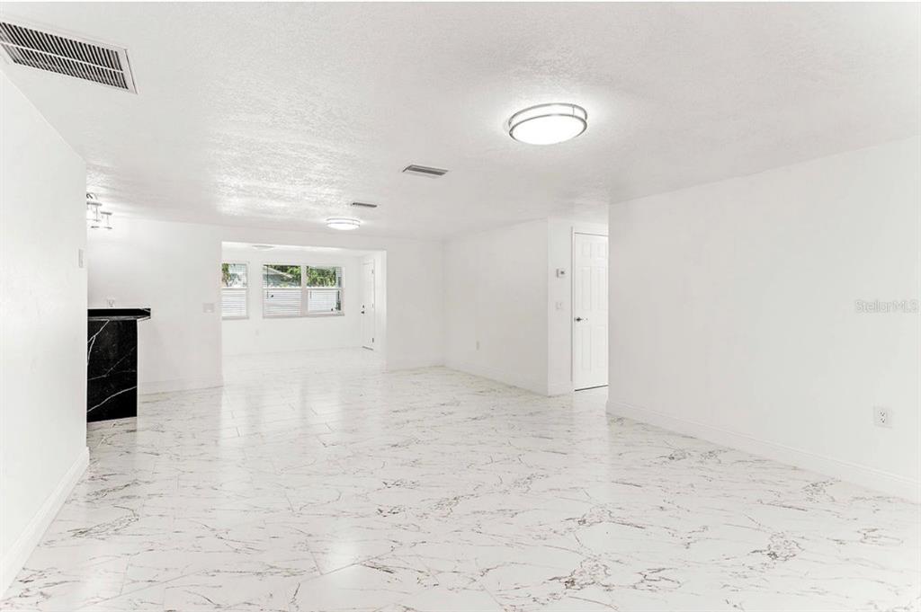 A bright, open-concept living area features white walls and polished white marble-patterned tile flooring — 4609 IRENE LOOP, NEW PORT RICHEY, FL
