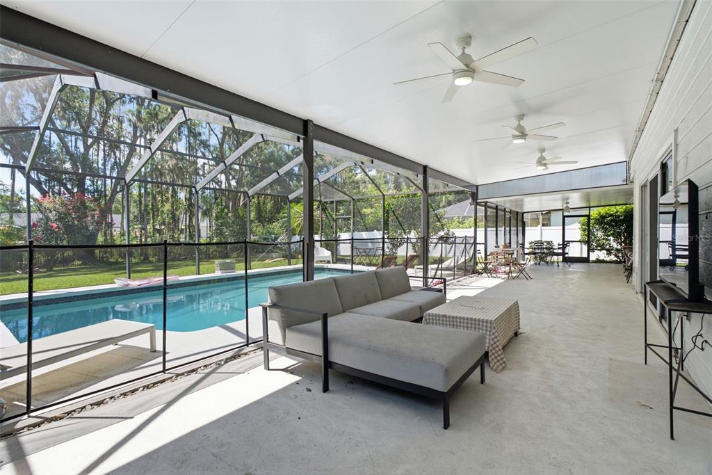 A covered patio features a gray sectional sofa, a pool, and a screened-in enclosure — 16909 ROLLING ROCK DRIVE, TAMPA, FL