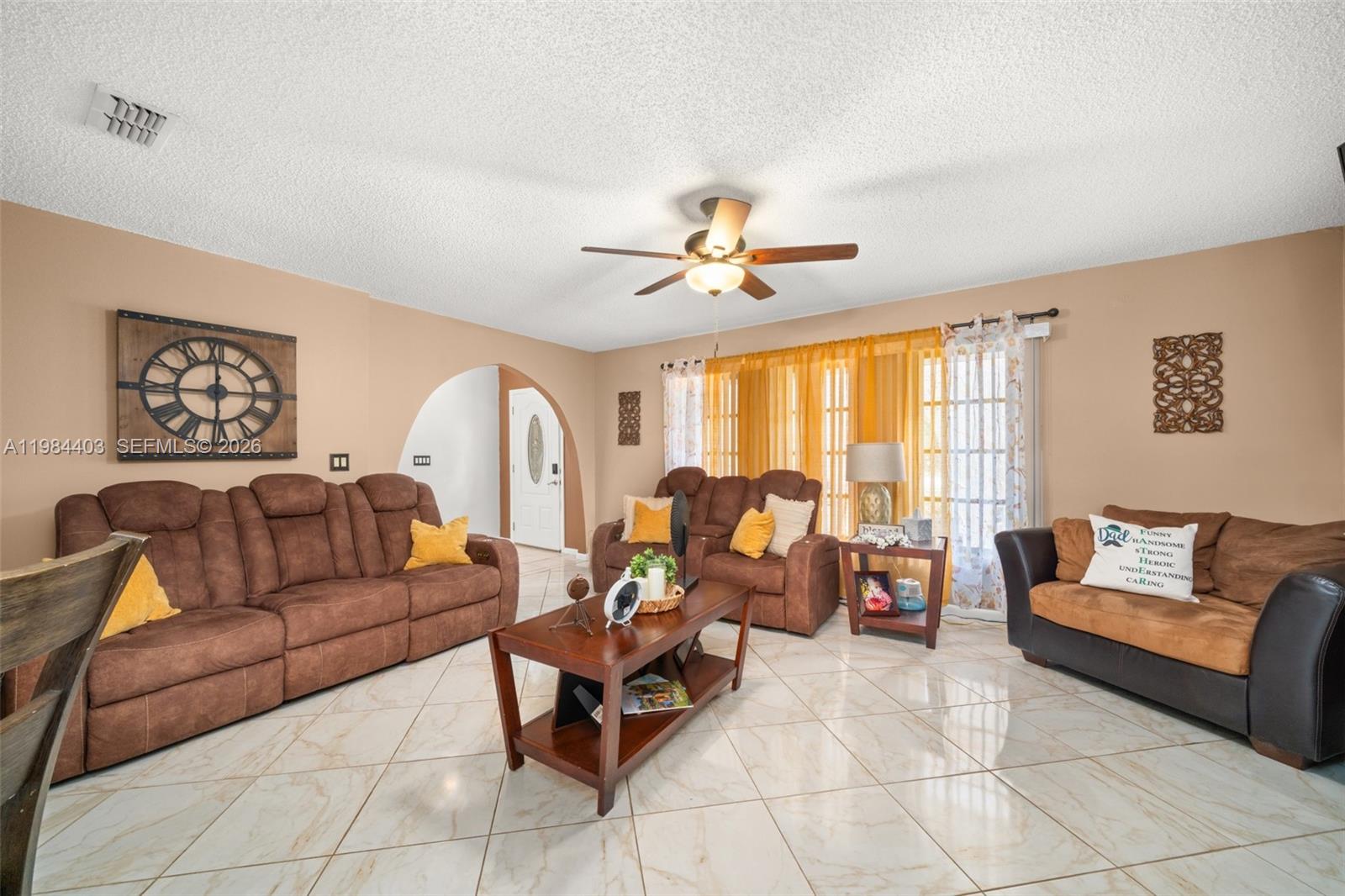 A living room features brown sofas, a coffee table, and tile flooring under a ceiling fan — 4201 Westminster Road, Sebring FL Road, SEBRING, FL