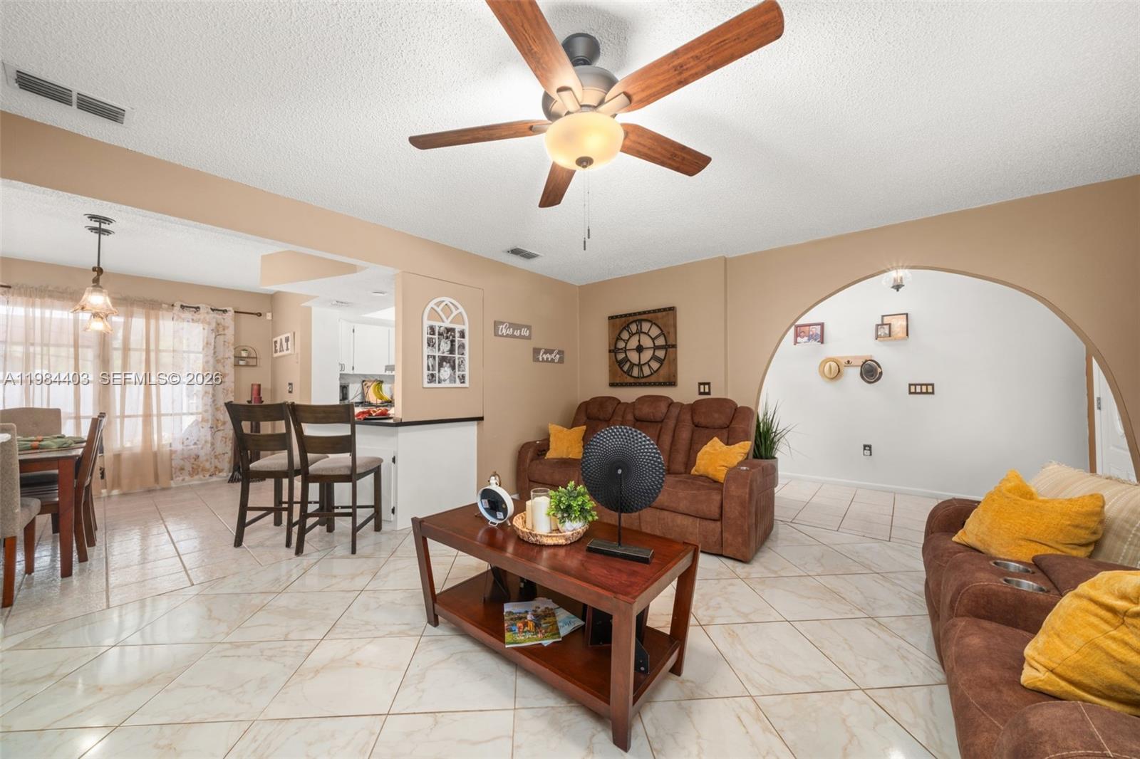 A living room with brown sofas, a coffee table, and an arched entryway to another room — 4201 Westminster Road, Sebring FL Road, SEBRING, FL