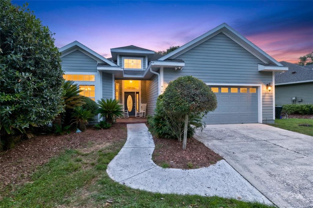 A single-story house with blue siding, a two-car garage, and a concrete walkway at dusk — 914 SW 83RD TERRACE, GAINESVILLE, FL