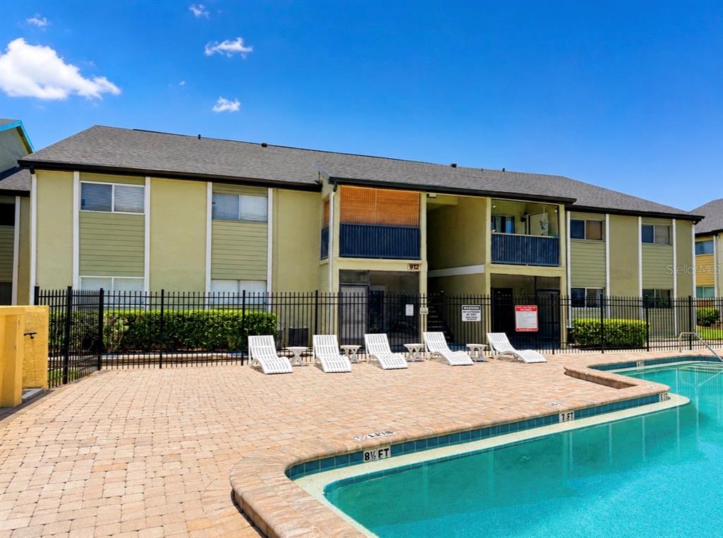 A swimming pool with a brick deck sits in front of a two-story apartment building — 912 LAKE DESTINY ROAD UNIT D, ALTAMONTE SPRINGS, FL