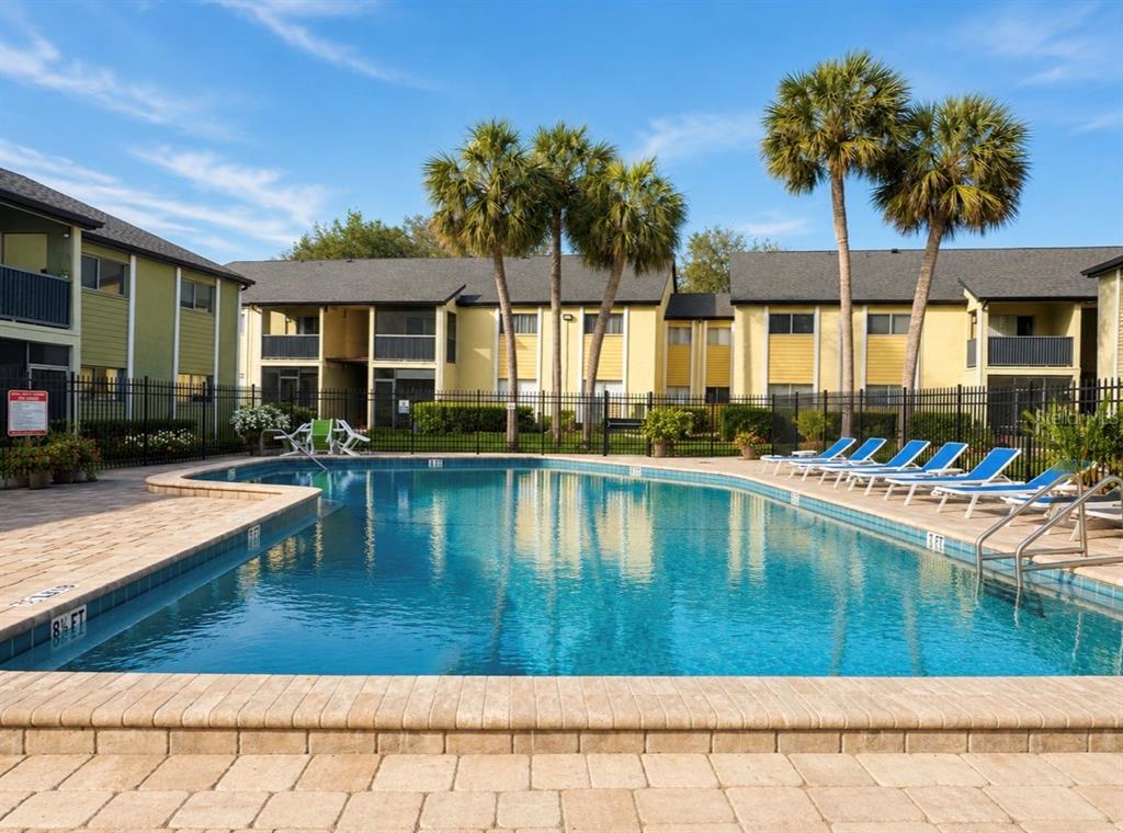 A swimming pool surrounded by a brick deck and apartment buildings under a blue sky — 912 LAKE DESTINY ROAD UNIT D, ALTAMONTE SPRINGS, FL