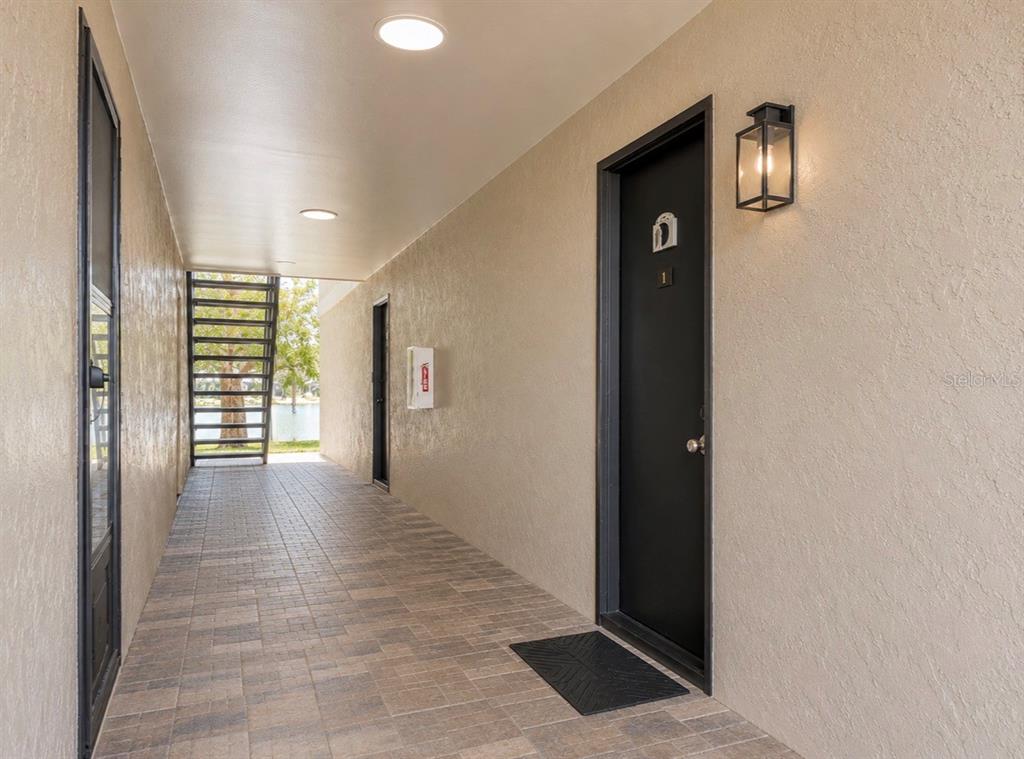 A covered outdoor walkway features a black door, a wall-mounted light, and a metal staircase — 912 LAKE DESTINY ROAD UNIT D, ALTAMONTE SPRINGS, FL